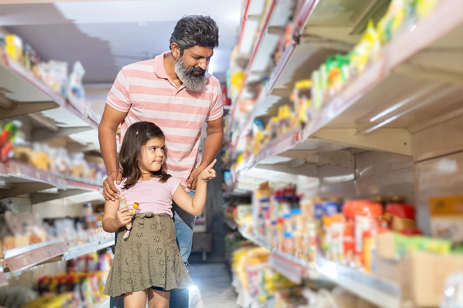 Happy indian father and daughter shopping for groceries at the supermarket